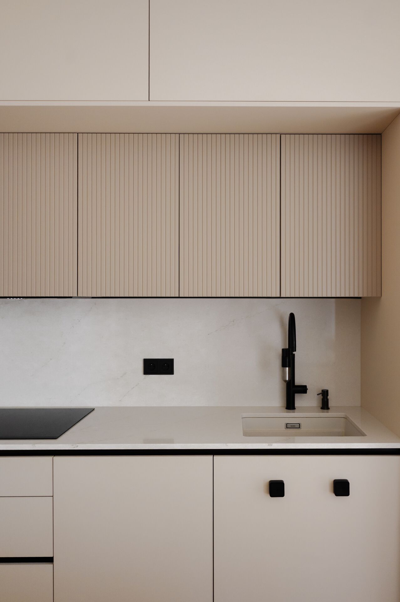 Detail of a black kitchen tap and hob set into a white worktop