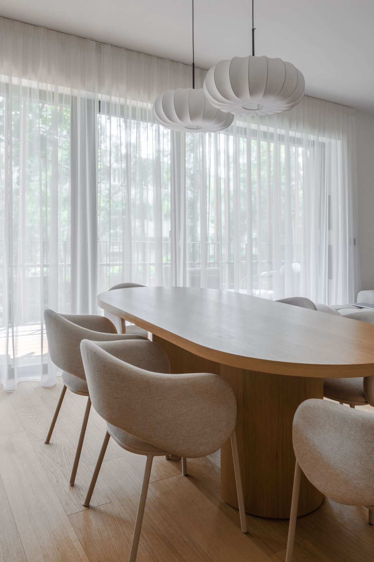 Dining corner with an oval oak table and a sheer curtain