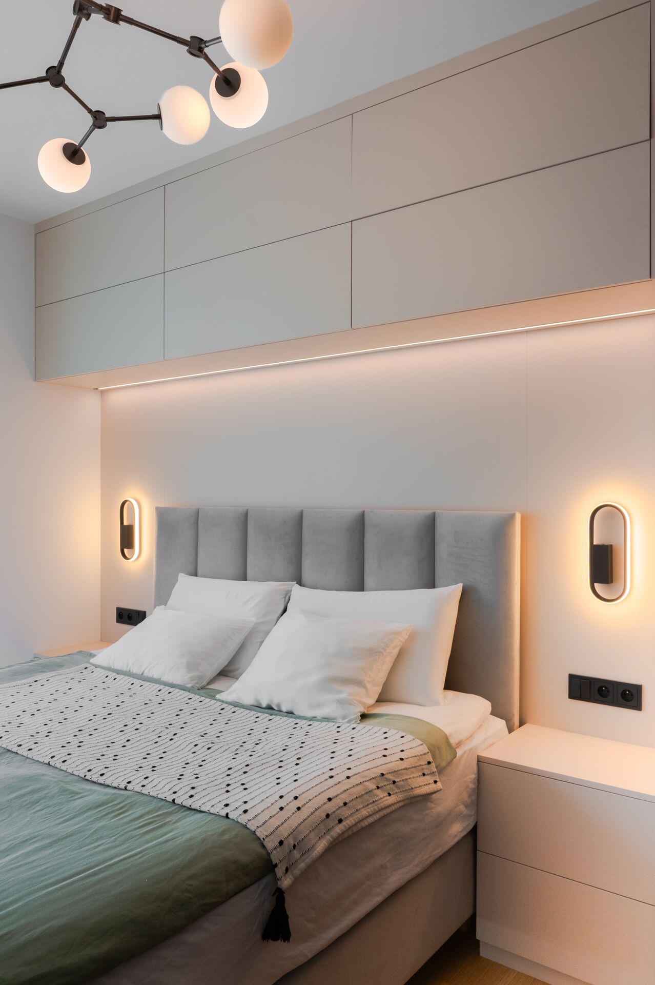 Evening mood in the bedroom with wall lights glowing beside the headboard