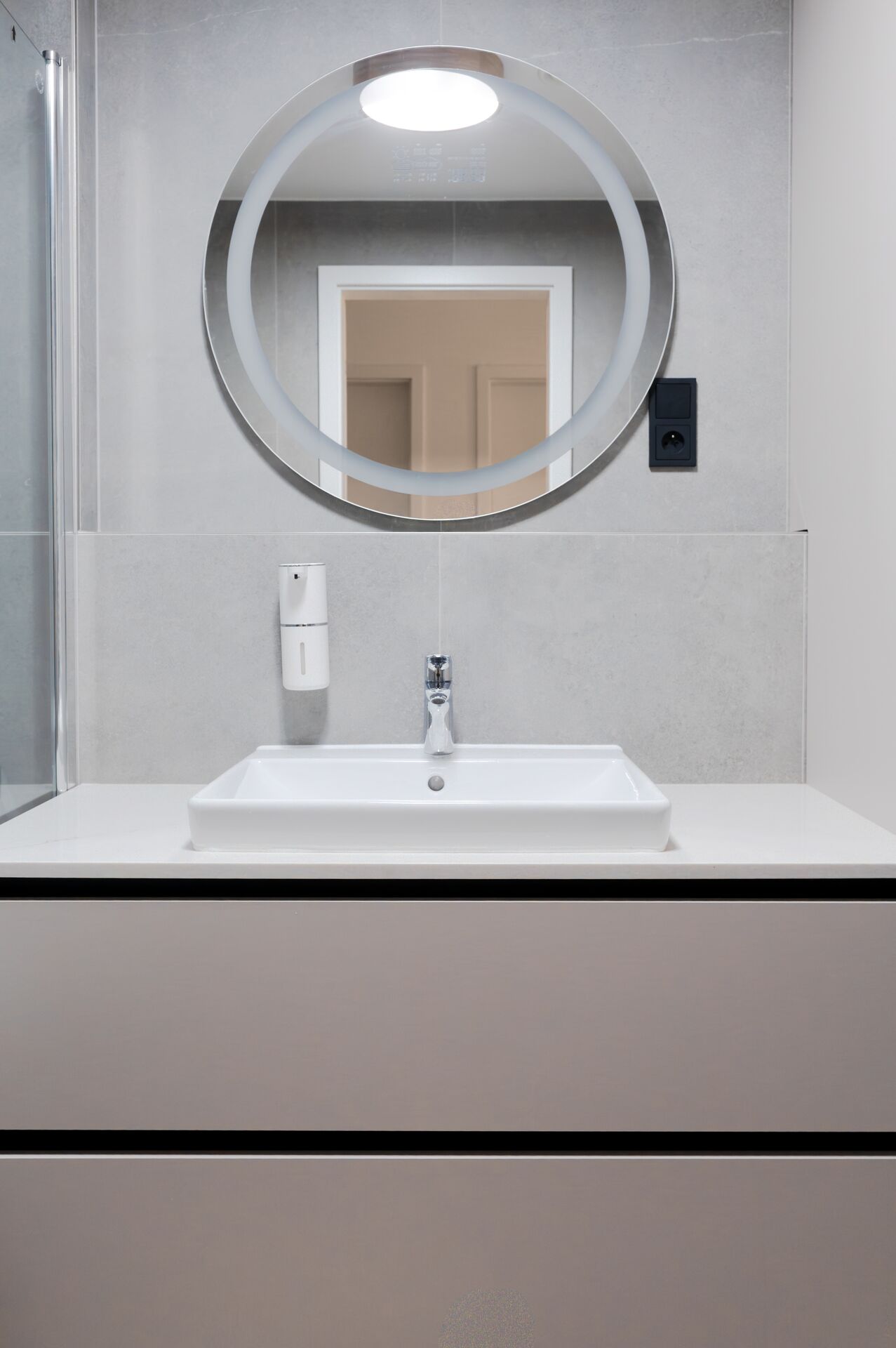 Bathroom with a round backlit mirror and a washbasin cabinet