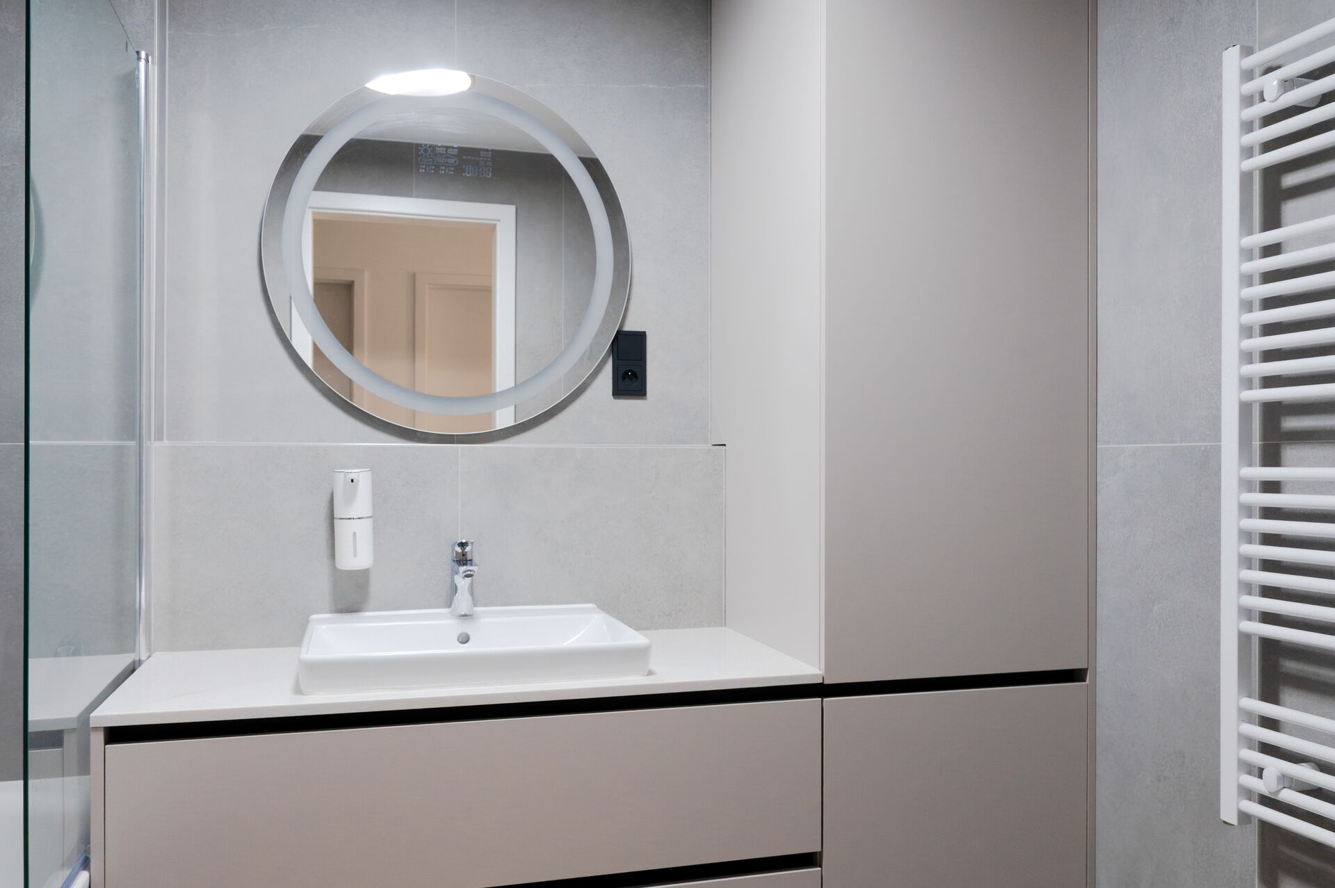 Shower enclosure, white towel radiator and grey bathroom tiling